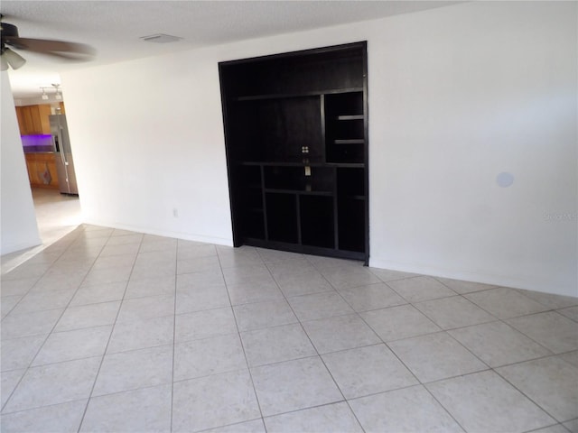 tiled empty room featuring a textured ceiling and ceiling fan