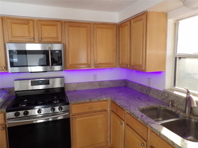 kitchen with sink, plenty of natural light, stainless steel appliances, and a textured ceiling