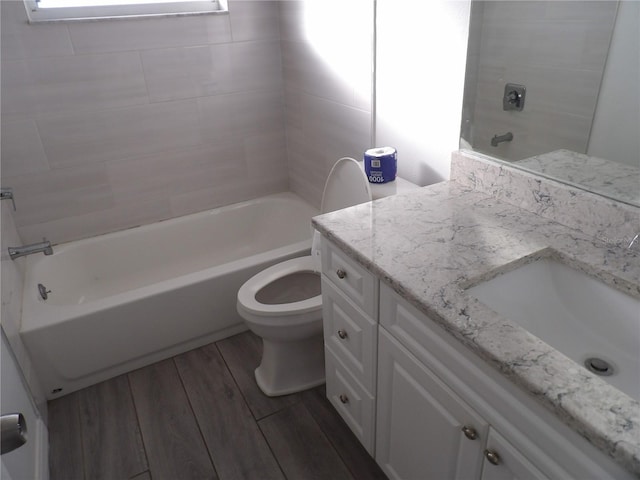 full bathroom with vanity, tiled shower / bath, wood-type flooring, and toilet