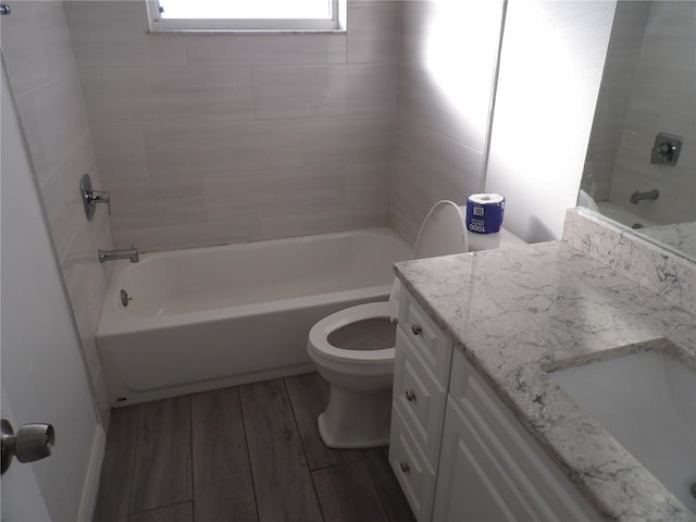 full bathroom with vanity, hardwood / wood-style floors, tiled shower / bath, and toilet