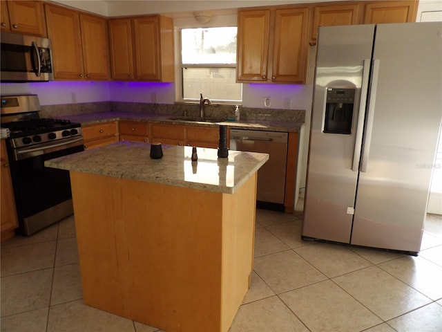 kitchen with sink, light tile patterned floors, a kitchen island, stone counters, and stainless steel appliances