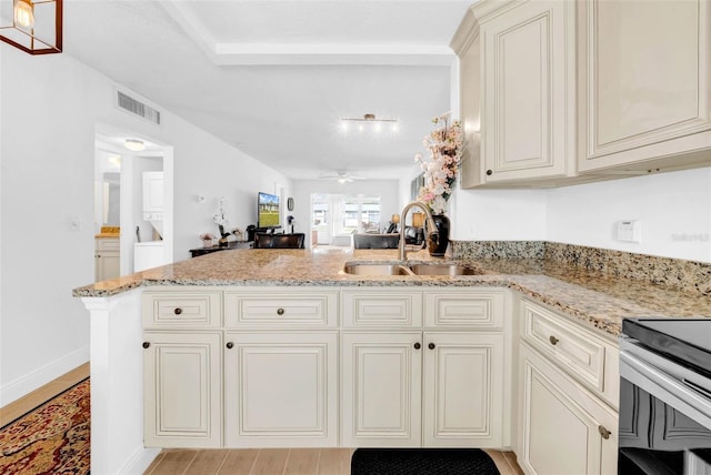 kitchen featuring ceiling fan, sink, light stone counters, and kitchen peninsula