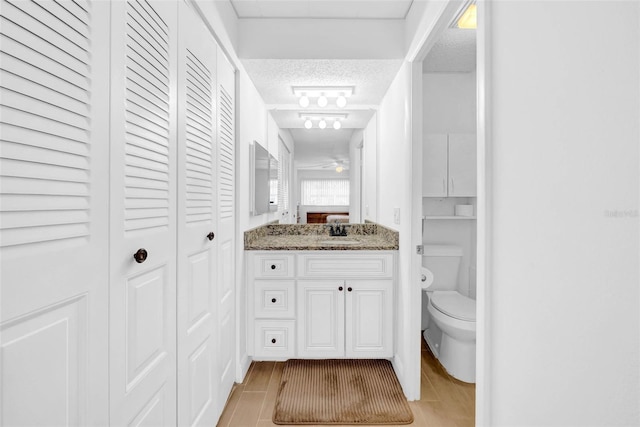 bathroom featuring vanity, toilet, hardwood / wood-style floors, and a textured ceiling