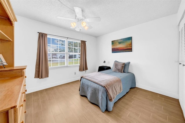 bedroom with ceiling fan, a textured ceiling, and light wood-type flooring