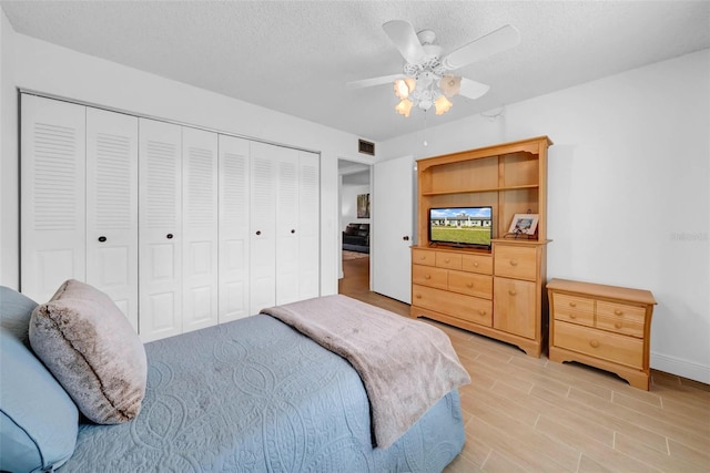 bedroom with ceiling fan, light hardwood / wood-style flooring, a closet, and a textured ceiling