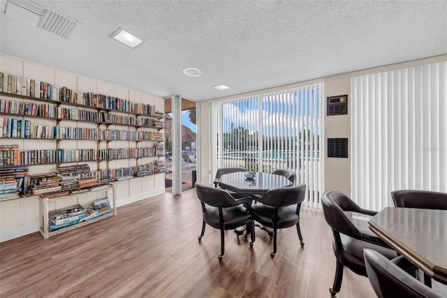 dining area featuring floor to ceiling windows, hardwood / wood-style floors, and a textured ceiling