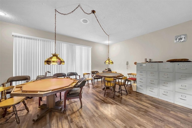 dining space with hardwood / wood-style floors and a textured ceiling