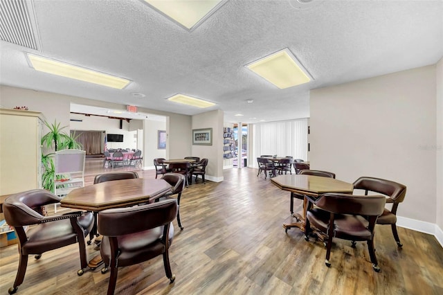 dining area with wood-type flooring and a textured ceiling