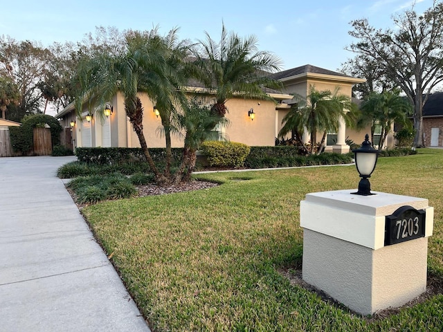 view of front facade featuring concrete driveway, a front lawn, an attached garage, and stucco siding