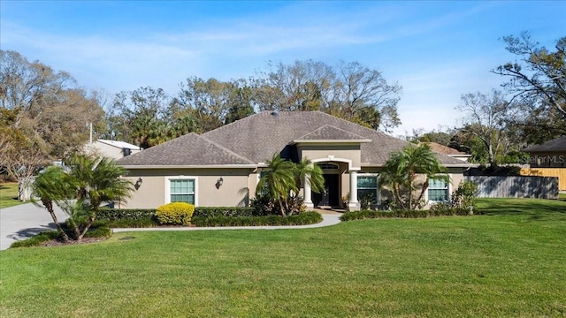 view of front of house with stucco siding, fence, and a front yard