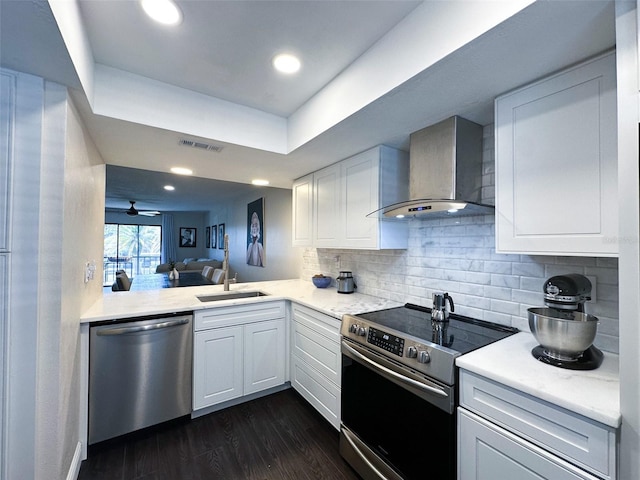 kitchen with visible vents, white cabinets, dark wood-style floors, appliances with stainless steel finishes, and wall chimney range hood