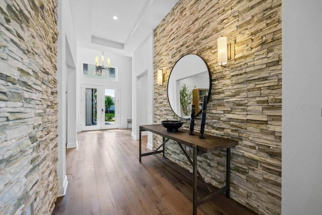 hallway featuring a towering ceiling, an inviting chandelier, dark hardwood / wood-style flooring, and french doors