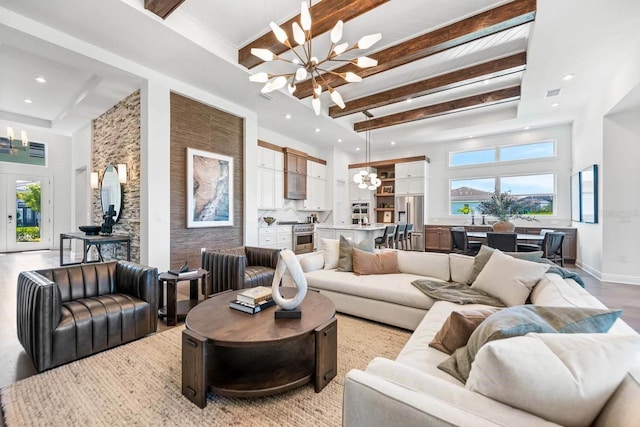 living room featuring beamed ceiling, a wealth of natural light, a chandelier, and a high ceiling