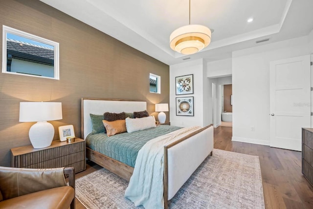 bedroom with a raised ceiling and hardwood / wood-style flooring