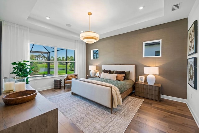 bedroom with wood-type flooring and a raised ceiling