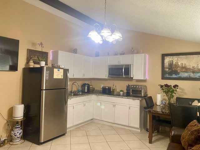 kitchen featuring stainless steel appliances, white cabinetry, lofted ceiling, and sink