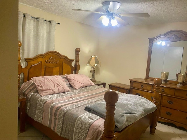 bedroom with ceiling fan, light tile patterned floors, and a textured ceiling