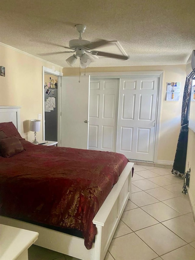 bedroom with ceiling fan, light tile patterned floors, a textured ceiling, and a closet