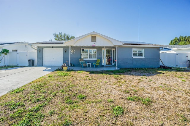 single story home featuring a porch, a garage, a front yard, and solar panels