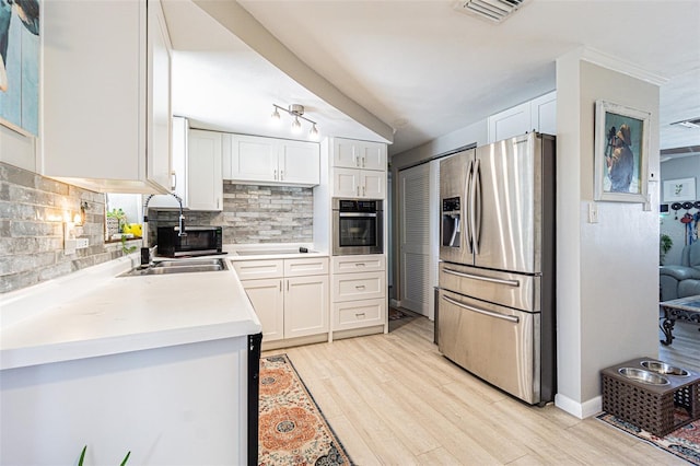 kitchen with stainless steel appliances, sink, white cabinets, and backsplash