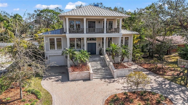 view of front of property featuring metal roof, a balcony, covered porch, decorative driveway, and a standing seam roof