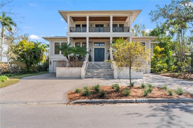 view of front of property with stairs, decorative driveway, an attached garage, and a balcony