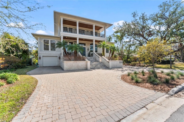 raised beach house with a balcony, a garage, and covered porch