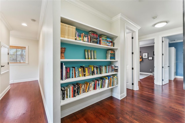 corridor with baseboards, ornamental molding, and wood finished floors