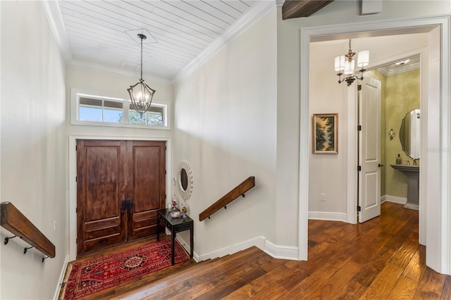 foyer entrance featuring crown molding, dark wood-type flooring, and a chandelier