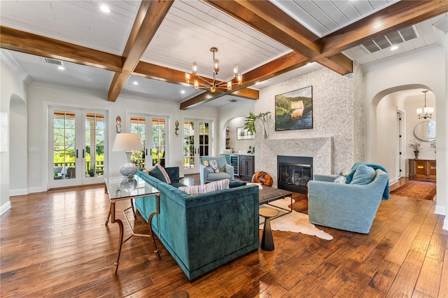 living room featuring arched walkways, french doors, an inviting chandelier, a large fireplace, and hardwood / wood-style floors