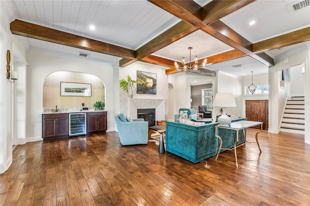 living room featuring a large fireplace, visible vents, wine cooler, dark wood-type flooring, and an inviting chandelier