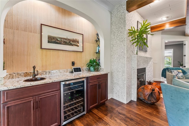 bar featuring a fireplace, sink, wine cooler, light stone countertops, and dark wood-type flooring