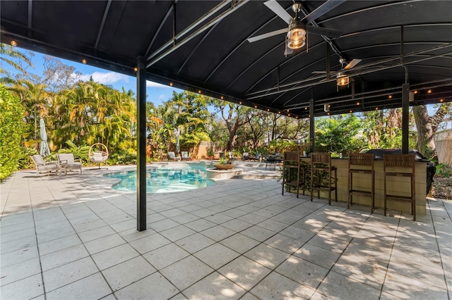 view of pool with a patio, ceiling fan, and exterior bar