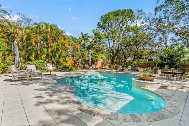 view of swimming pool with a patio area, a pool with connected hot tub, and fence