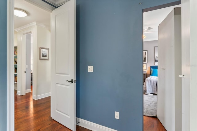 hall featuring baseboards, ornamental molding, and dark wood-type flooring