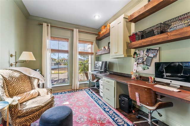 office space with dark wood-type flooring, ornamental molding, and built in desk