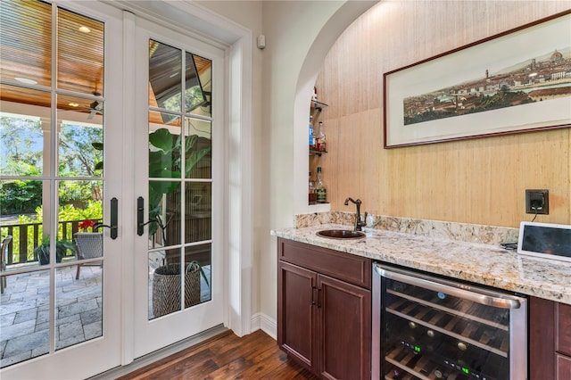 bar with light stone countertops, sink, dark wood-type flooring, and wine cooler