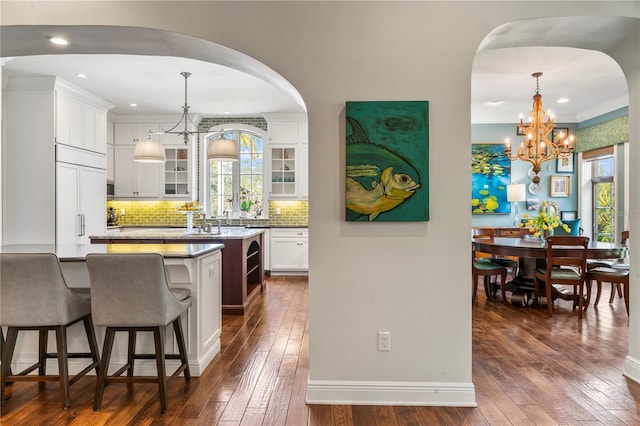 kitchen featuring dark wood-style floors, a wealth of natural light, glass insert cabinets, and a kitchen breakfast bar