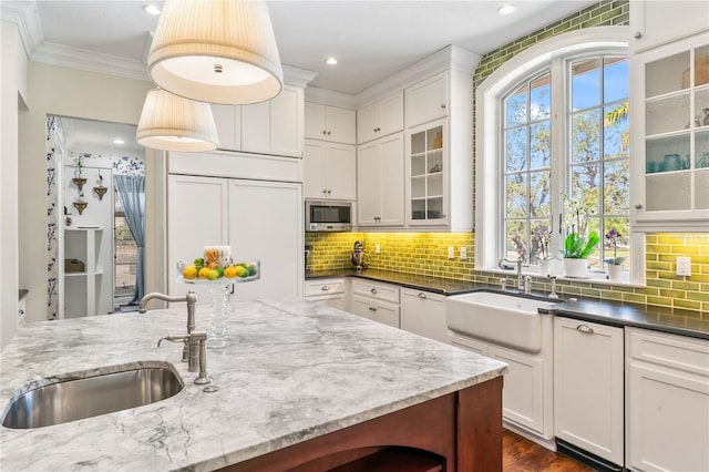 kitchen with white cabinetry, decorative light fixtures, sink, and dark stone countertops