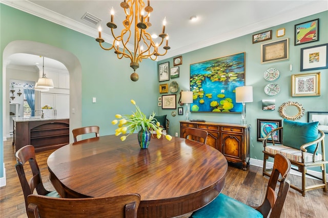 dining area featuring arched walkways, crown molding, visible vents, hardwood / wood-style floors, and baseboards