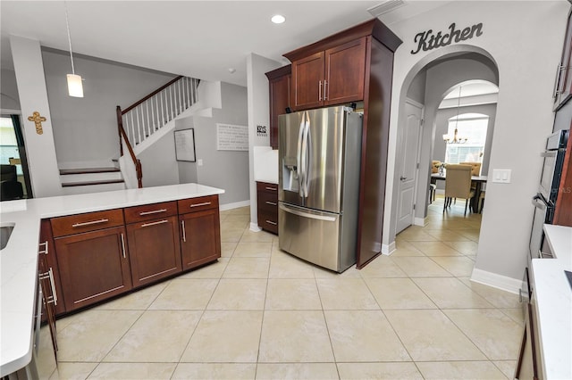 kitchen with light tile patterned floors, arched walkways, light countertops, and stainless steel fridge with ice dispenser