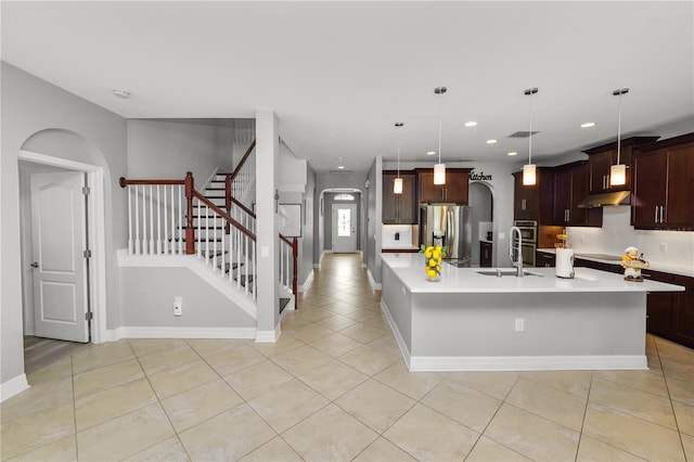 kitchen with arched walkways, stainless steel appliances, a sink, and light countertops