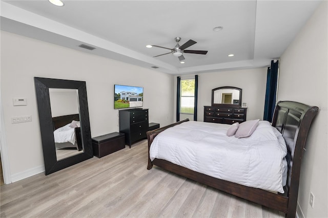 bedroom featuring visible vents, baseboards, a tray ceiling, light wood-style floors, and recessed lighting