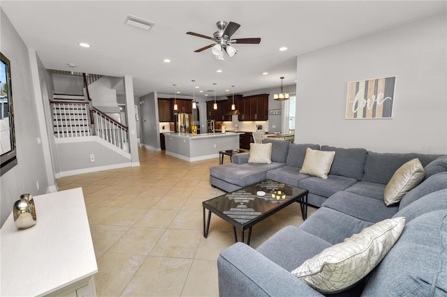 living area featuring recessed lighting, visible vents, stairs, light tile patterned flooring, and ceiling fan with notable chandelier