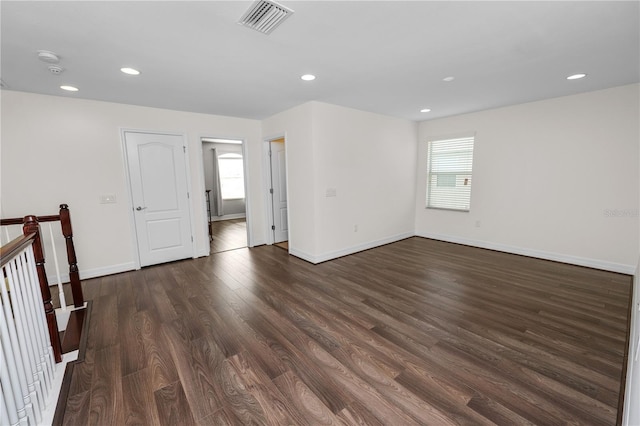 empty room with dark wood-style floors, recessed lighting, visible vents, and baseboards