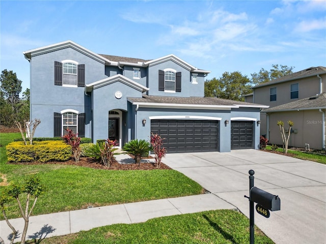 traditional home with concrete driveway, a front yard, and stucco siding