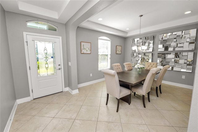 dining area with light tile patterned flooring, a raised ceiling, a wealth of natural light, and baseboards