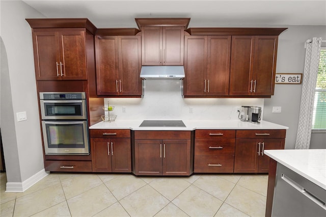 kitchen with double oven, light tile patterned flooring, black electric cooktop, under cabinet range hood, and light countertops