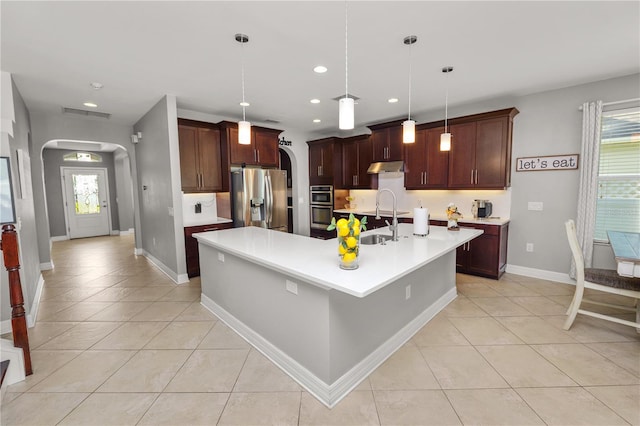 kitchen featuring a healthy amount of sunlight, appliances with stainless steel finishes, arched walkways, and a sink