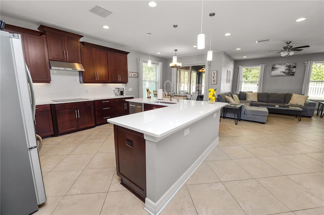 kitchen featuring black electric stovetop, under cabinet range hood, a sink, light countertops, and freestanding refrigerator